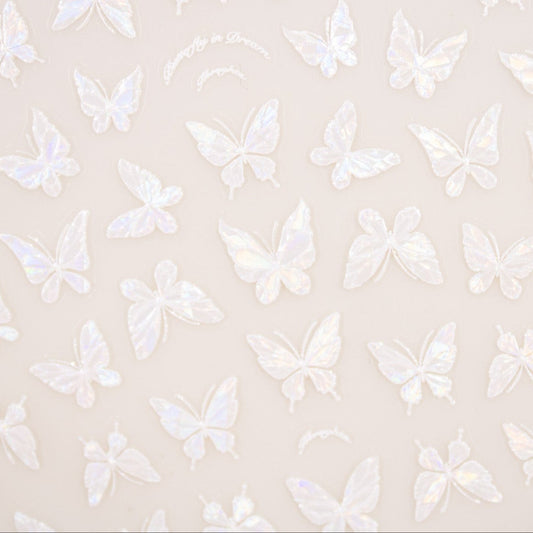 Close-up of delicate pearly butterfly nail decals catching the light.