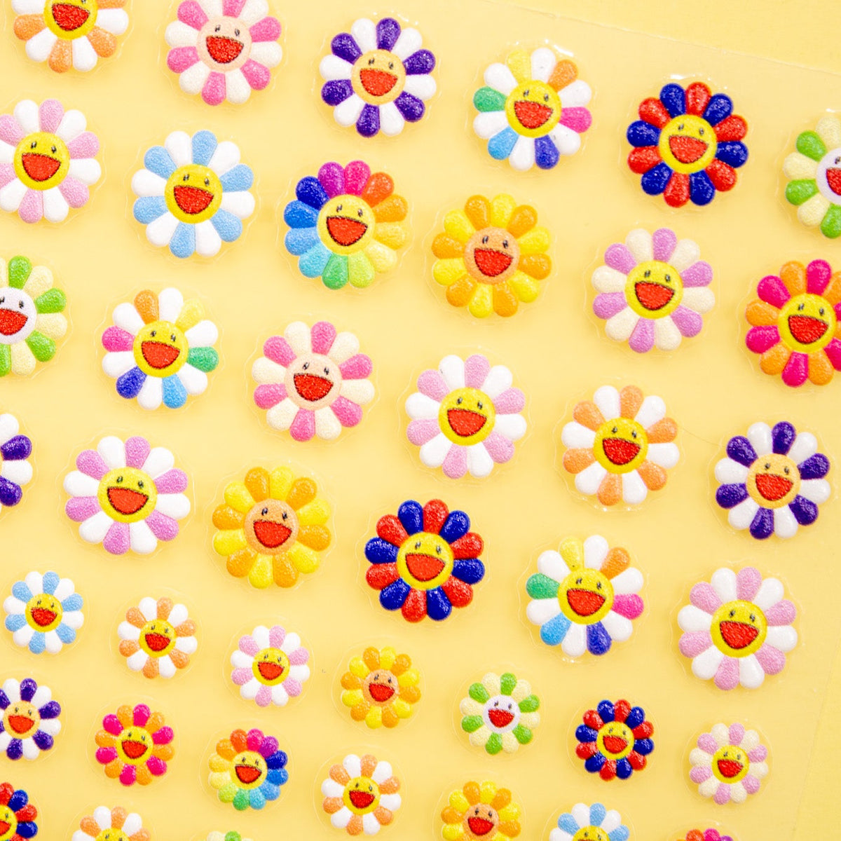 Angled shot of smiley daisy flower nail stickers in various sizes.