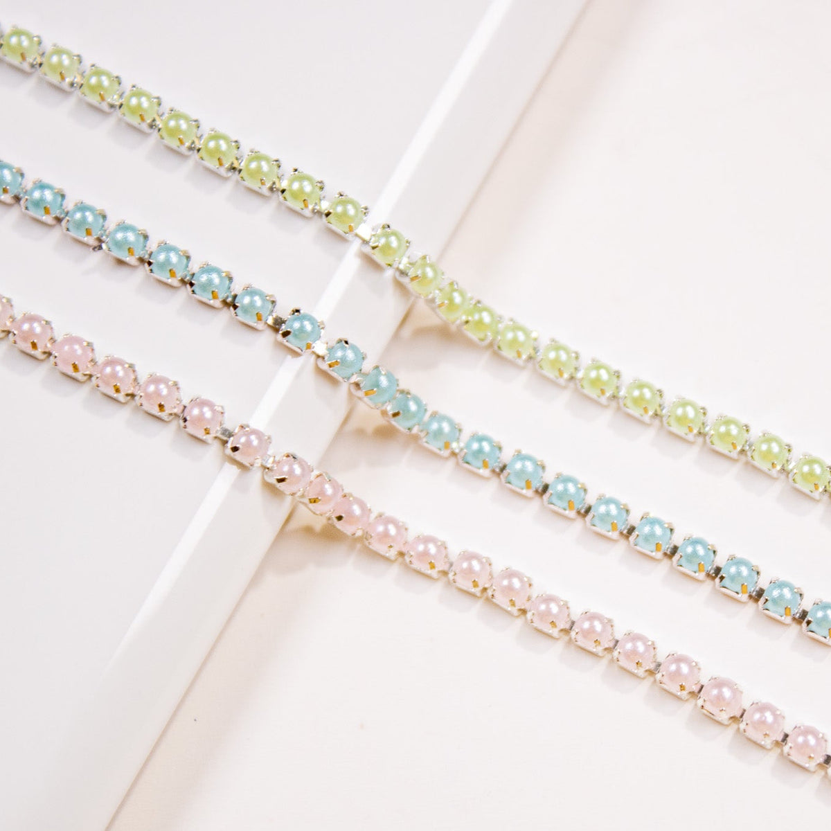 Pastel green, pink, and blue bead chains side by side.