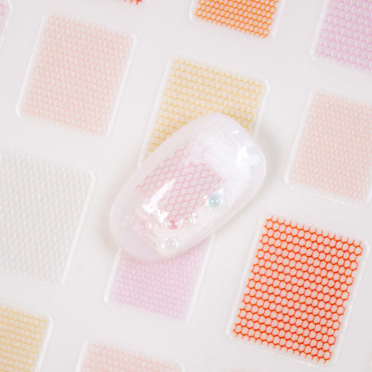 Warm tone mesh nail sticker sheet with white nail display tips showing applied pattern.