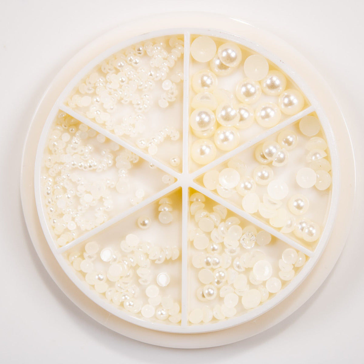 Round compartment storage wheel filled with various sizes of cream flatback half pearls.
