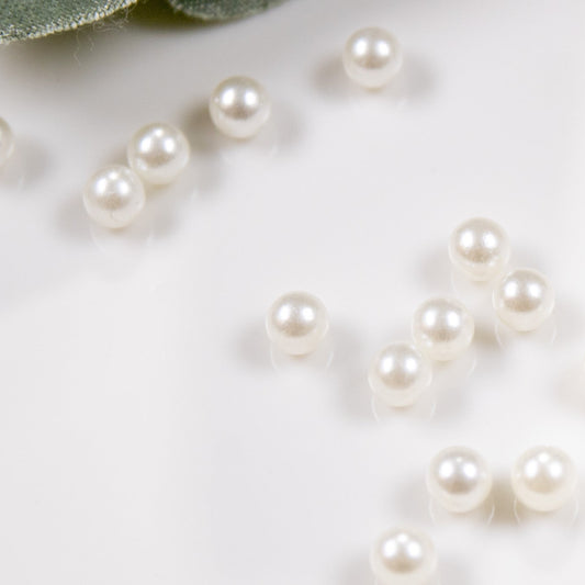 Close-up of cream round pearls scattered on a white surface.