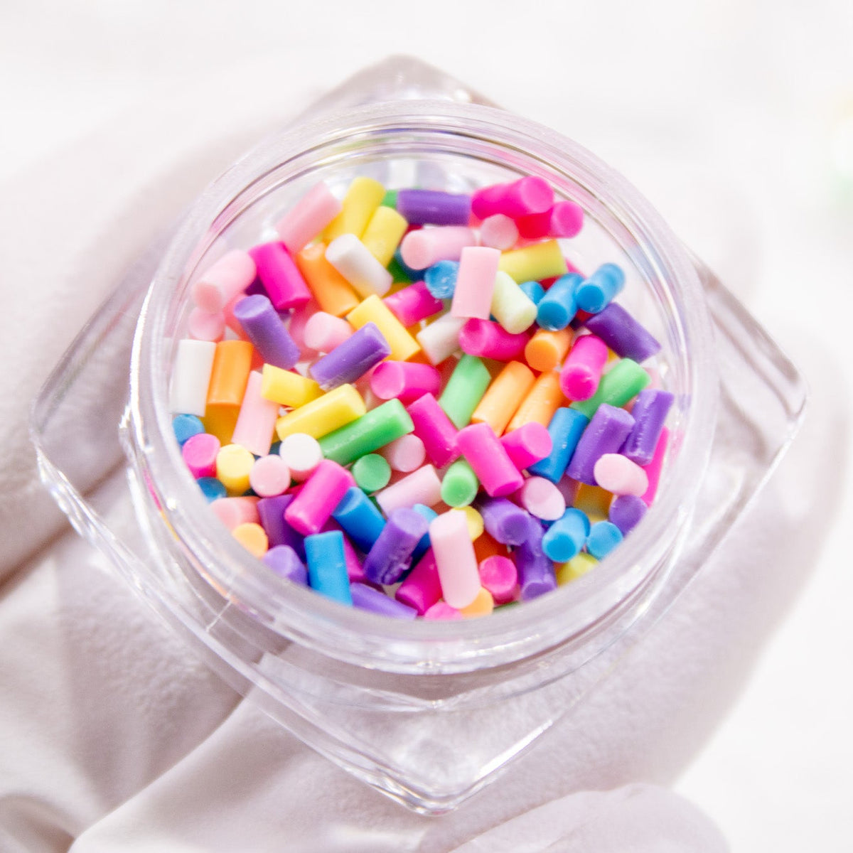 Close-up angled view of a open jar with colorful nail sprinkles.