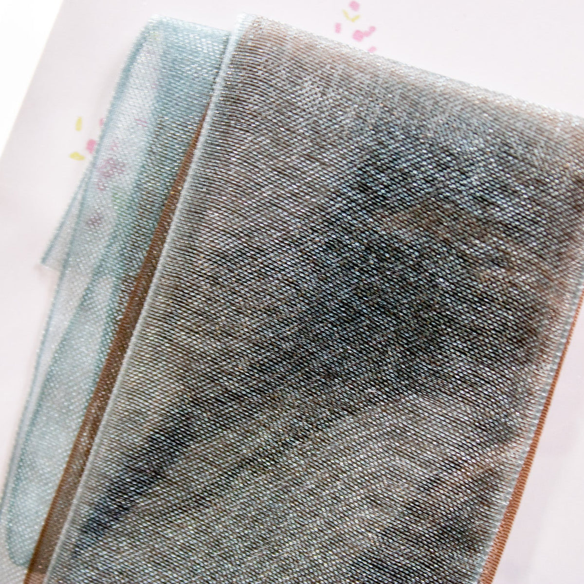 Close-up view of the sheer shimmer ribbon strip held over paper.