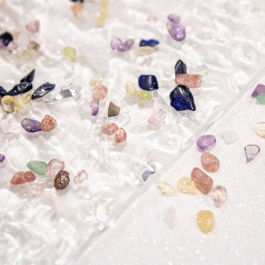 Multicolor gemstone-style pebble stones scattered across a white background.