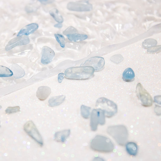 Icy blue pebble stones scattered across a white surface.