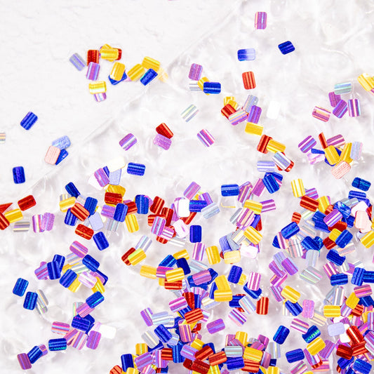 Multicolor ultra-mini bar glitter pieces scattered across a white background.