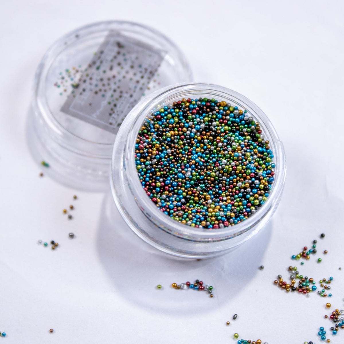 Angled shot of a jar filled with micro bullion caviar beads for nail art.