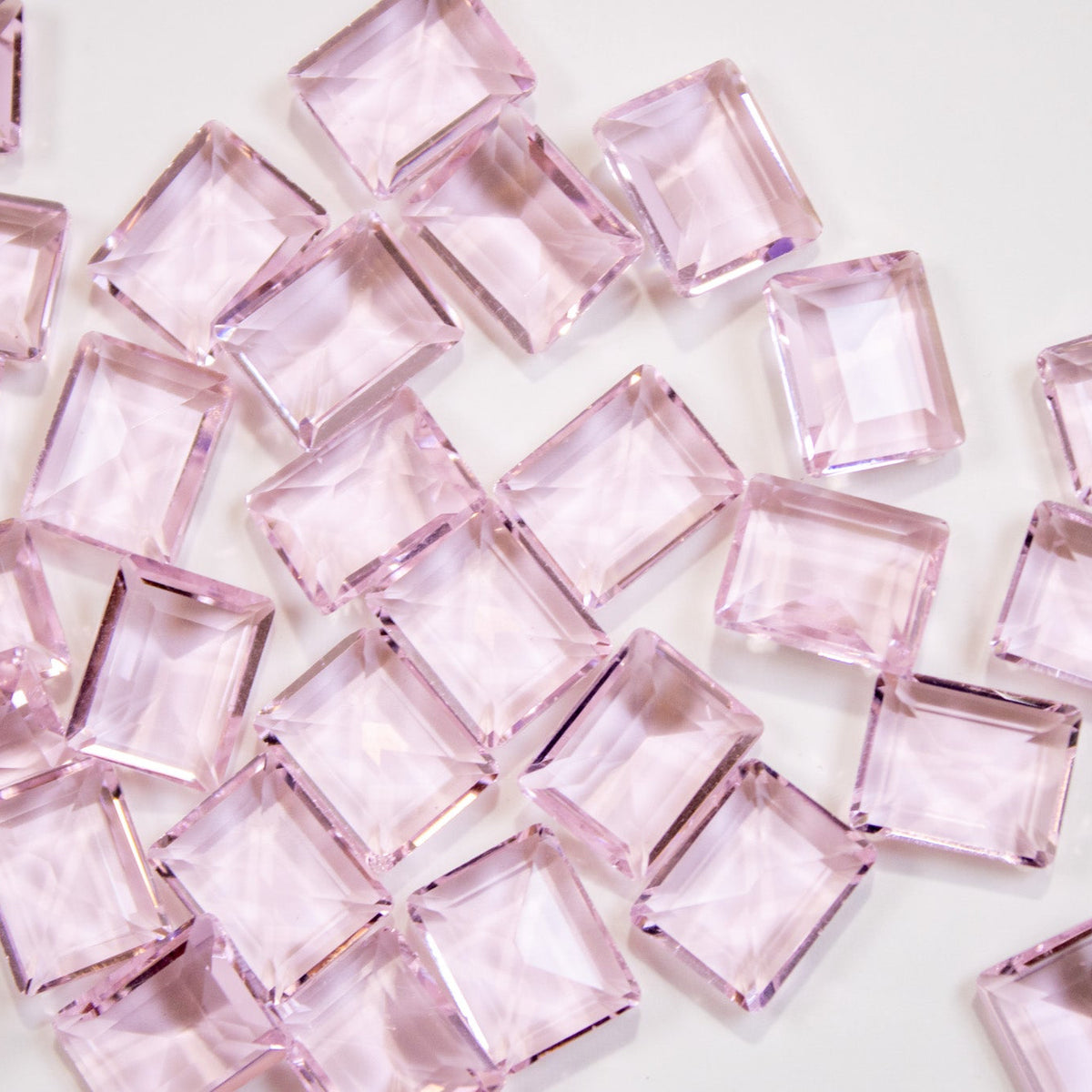Scattered light pink emerald-cut rectangular crystal nail stones.