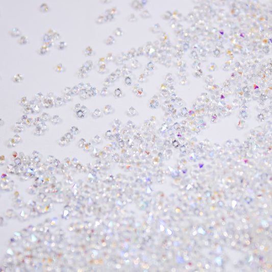 Close-up view of clear iridescent Pixie Dust micro crystals scattered across a white background.