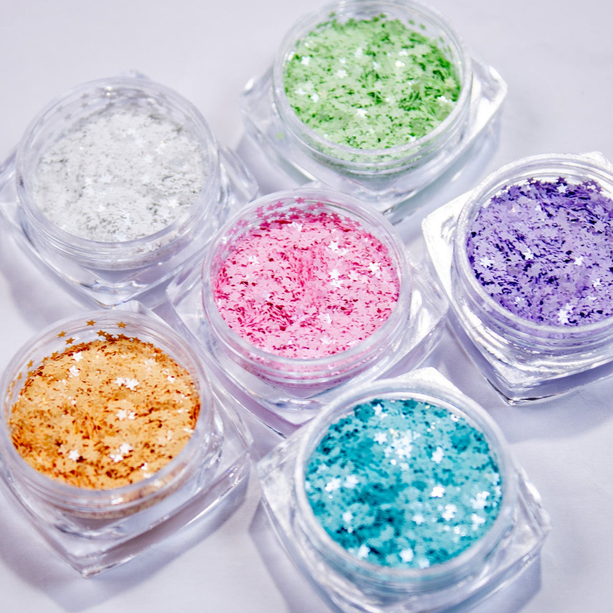 Six small jars of colorful micro star nail glitter grouped together.