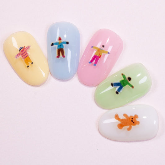 Row of five pastel press-on nail swatches decorated with tiny illustrated people nail charms.