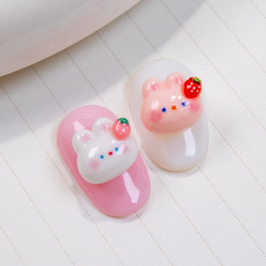 Pink press-on nail swatch paired with white strawberry bunny 3D nail charm and white press-on nail swatch paired with pink strawberry bunny 3D nail charm.