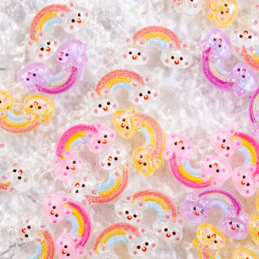 Assorted pastel rainbow bunny 3D nail charms scattered across a white textured surface.