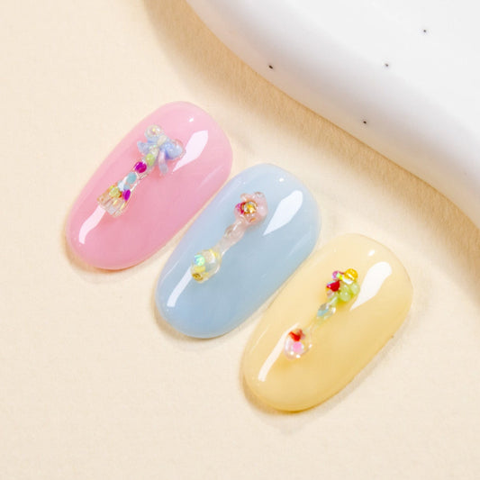 Pink, blue, and yellow press-on nail swatches decorated with pastel mini spoon and fork 3D nail charms.