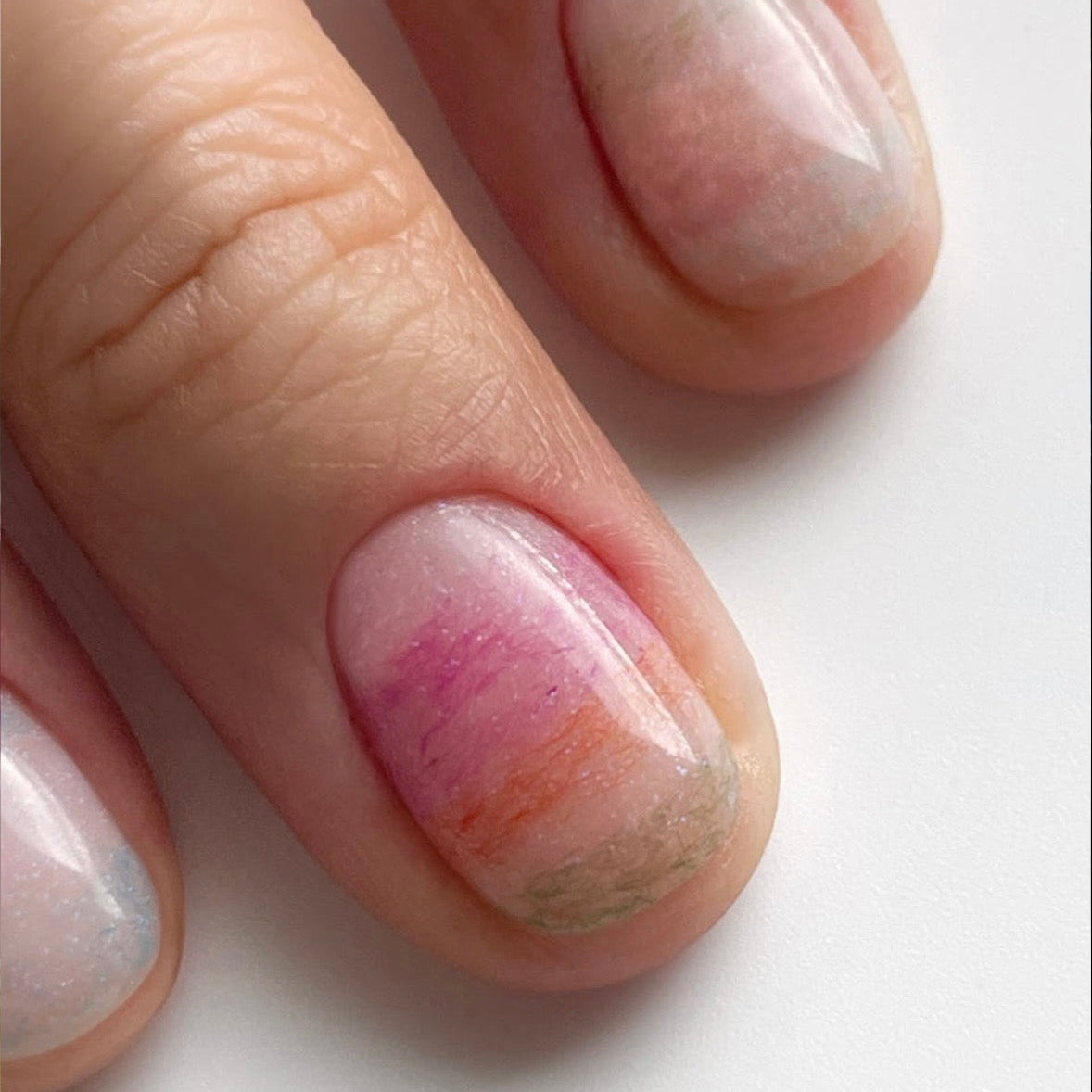 Close-up of manicured nail showing a soft pink velvet powder application.
