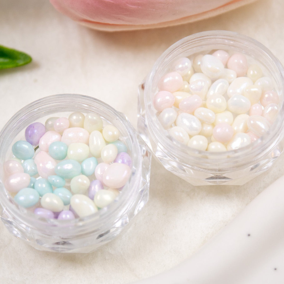 Angled shot of two clear jars displaying Cotton Candy and Fairy Mix pastel jelly pebble nail stones side by side.