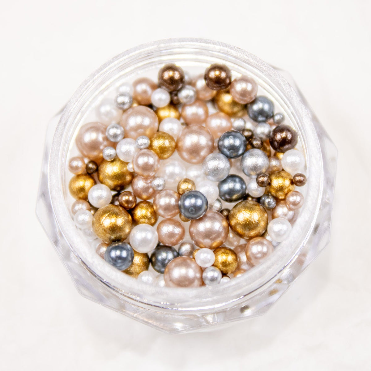 Top-down view of an open jar packed with champagne, white, bronze, and mocha Cocoa Mix beads.