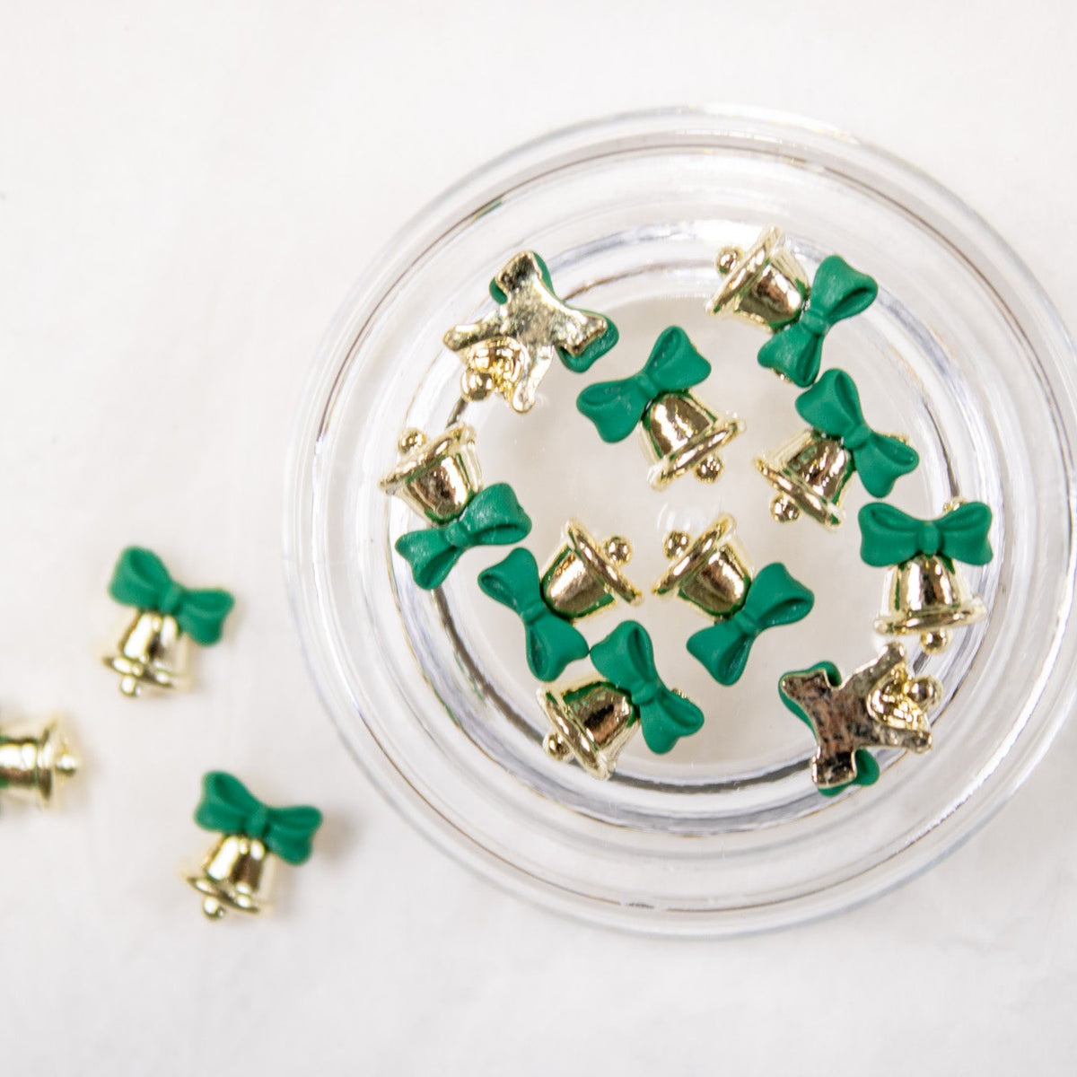 Open jar filled with 3D gold jingle bell charms featuring green bows.