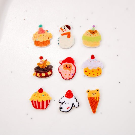 Flat lay arrangement of winter bakery nail charms including cupcakes, snowmen, Santa, and dessert pieces.