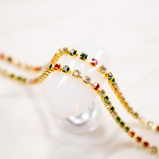 Strands of festive red, green, and clear rhinestone nail chain displayed against a clean background.