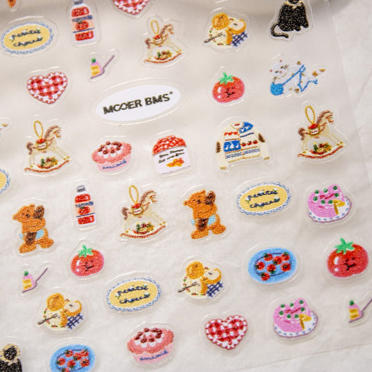 Detailed close-up of bottom section of Cozy Winter nail sticker sheet featuring bear, sweater, and heart decals.