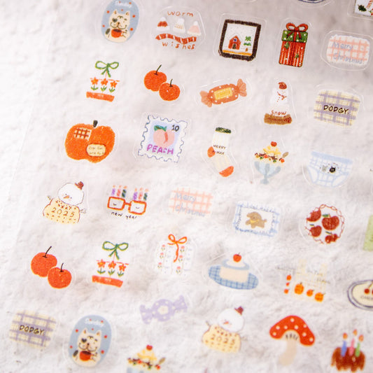 Angled shot of a sheet packed with cozy winter nail sticker decals like cherries, snowmen, and gifts.