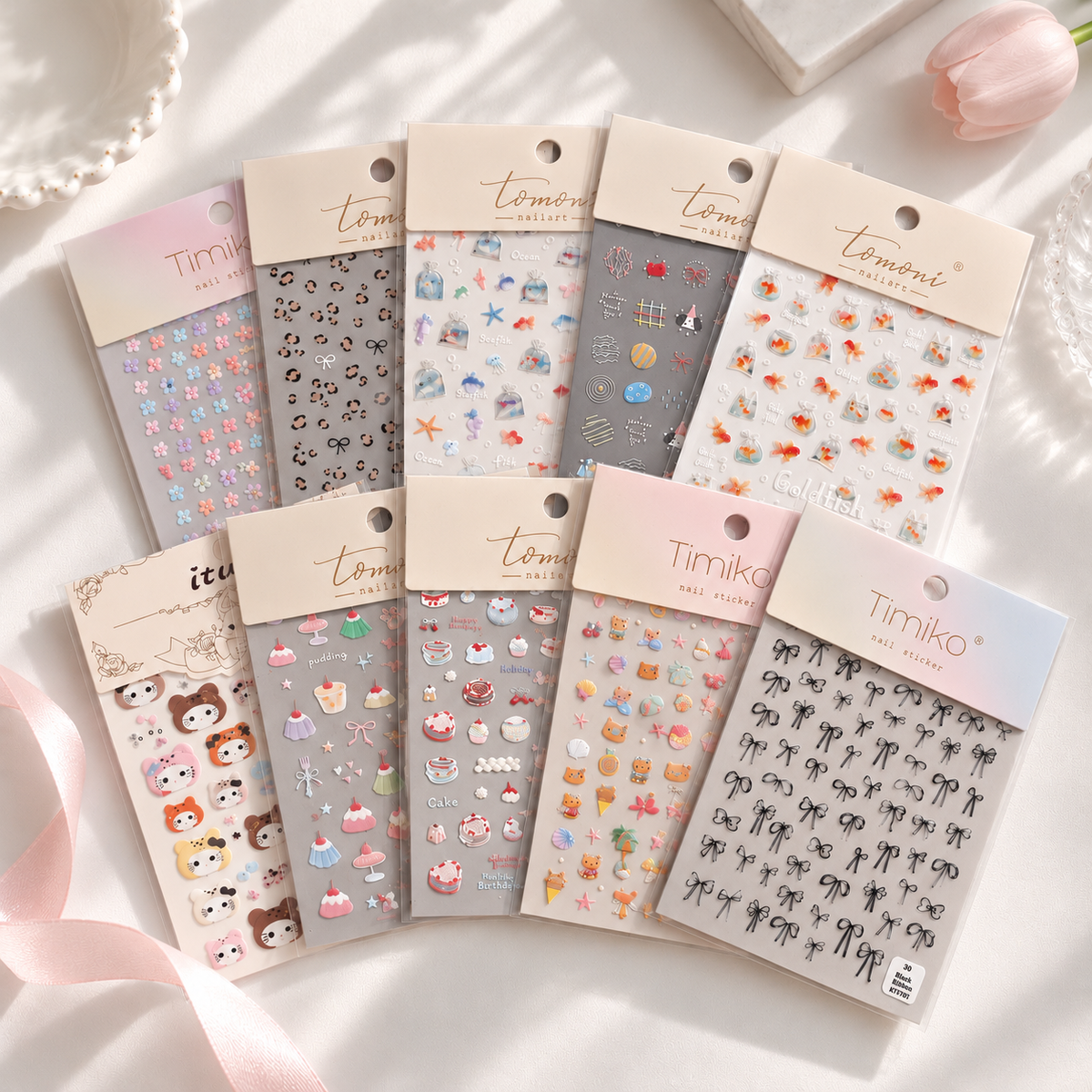 Mystery Nail Sticker Pack featuring 10 assorted nail sticker sheets with cute animal, floral, bow, dessert, and playful designs arranged on a soft white background with pink ribbon accents.