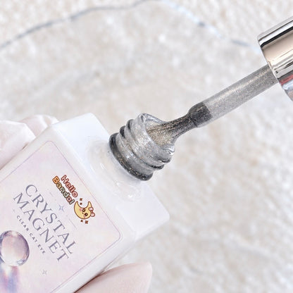 Close-up of the Crystal Magnet Gel polish bottle with brush applicator showing silver magnetic shimmer particles.