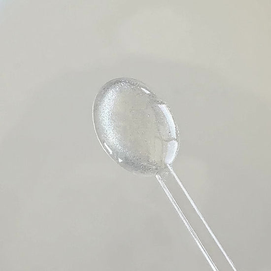 Clear cat eye gel applied onto a clear spoon to showcase the shimmering magnetic glitter effect in motion.