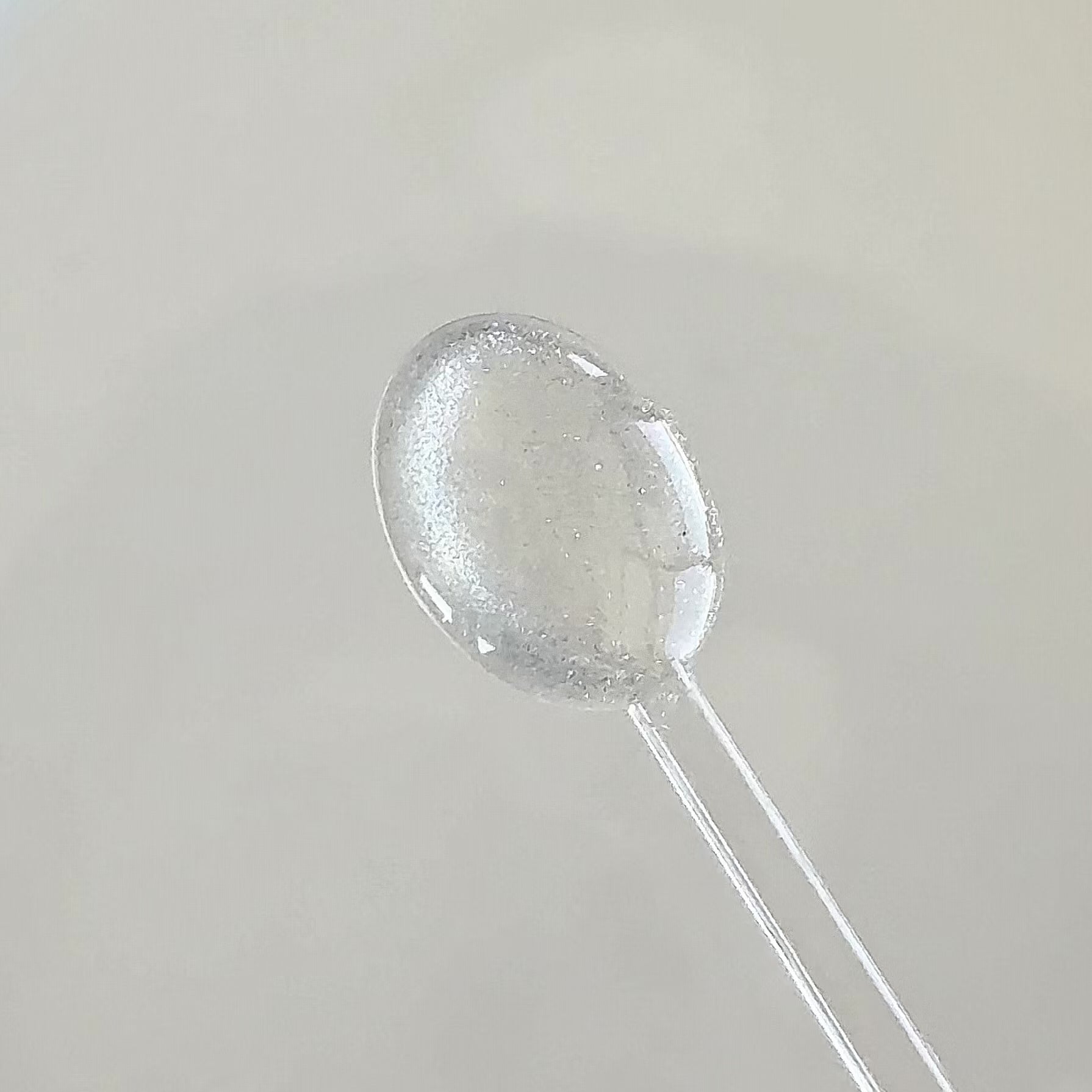 Clear cat eye gel applied onto a clear spoon to showcase the shimmering magnetic glitter effect in motion.